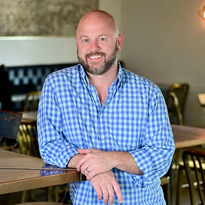 Chef Travis Lenig smiling inside Field & Tides.